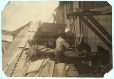 Charlie McBride, 12 Jahre alt, holt 10 Stunden lang Holz aus einem Schacht bei der Miller und Vidor Lumber Company, Beaumont, Texas, wofür er 50 Cent verdient, während der andere Junge es auf einer ungeschützten Kreissäge sägt, 191 von Lewis Wickes Hine